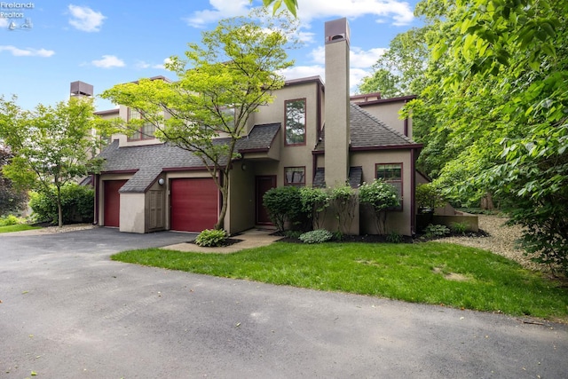4370 Marin Woods Dr Unit D, Port Clinton, OH 43452 - view of front facade with stucco siding, driveway, a chimney, roof with shingles, and a front lawn