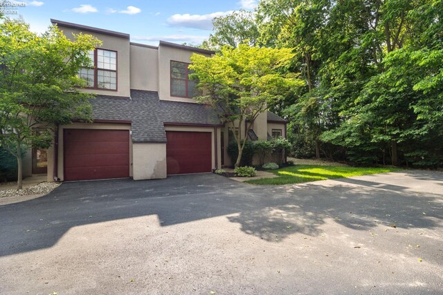 4370 Marin Woods Dr Unit D, Port Clinton, OH 43452 - view of front facade with a garage, a shingled roof, driveway, and stucco siding