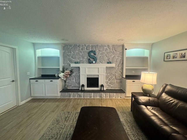505 E Stoneplace Dr, Sandusky, OH 44870 - living room with a textured ceiling, wood finished floors, a stone fireplace, built in shelves, and baseboards