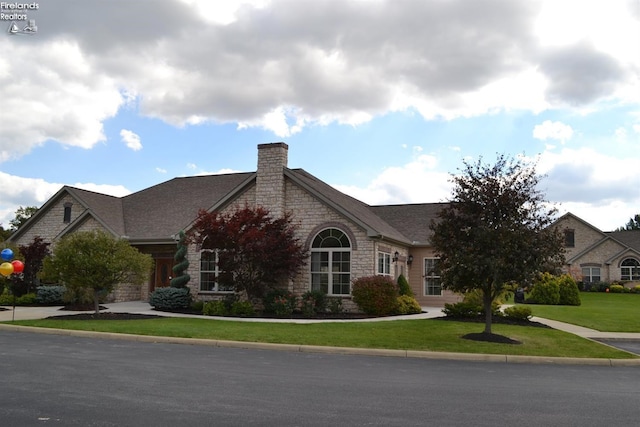 3826 Windsor Bridge Cir, Huron, OH 44839 - view of front of home with stone siding, a front lawn, and a chimney