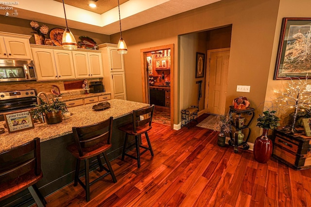3826 Windsor Bridge Cir, Huron, OH 44839 - kitchen featuring appliances with stainless steel finishes, decorative backsplash, a breakfast bar, hanging light fixtures, and dark wood-style flooring
