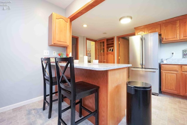 4647 Crk 175, Clyde, OH 43410 - kitchen featuring freestanding refrigerator, a breakfast bar, a peninsula, and light stone countertops