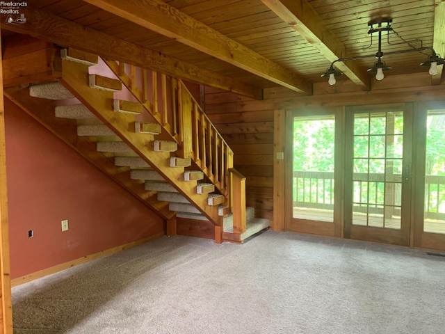 37 State Route 60, New London, OH 44851 - unfurnished living room with carpet floors, a wood ceiling with exposed beams, stairs, and wooden walls