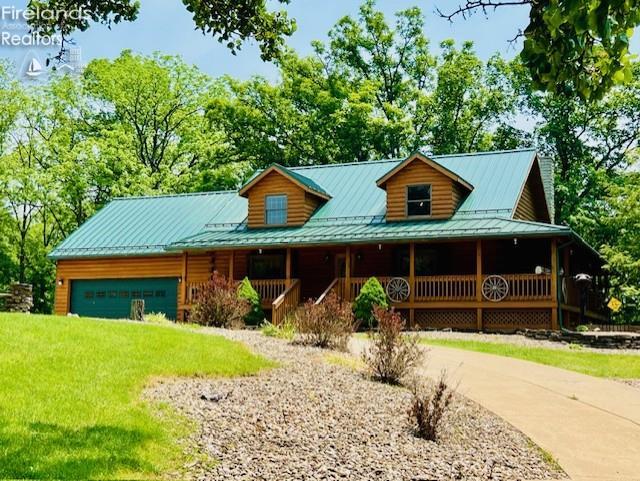 37 State Route 60, New London, OH 44851 - log cabin with driveway, covered porch, a garage, a standing seam roof, and a metal roof