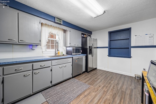 46320 Middle Ridge Rd, Amherst, OH 44001 - kitchen with appliances with stainless steel finishes, gray cabinetry, a textured ceiling, and wood finished floors