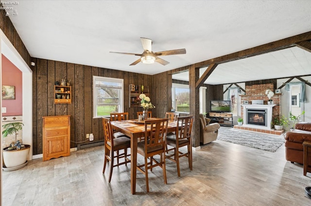 5191 N State Route 53, Tiffin, OH 44883 - dining room featuring light wood finished floors, a baseboard radiator, a fireplace, a ceiling fan, and wood walls