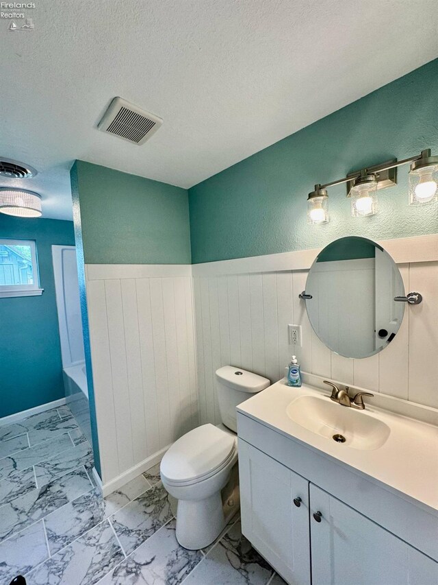 2150 Aspen Run, Sandusky, OH 44870 - bathroom with vanity, marble look tile flooring, wainscoting, and a textured ceiling