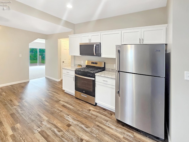217 Ott St, Clyde, OH 43410 - kitchen featuring appliances with stainless steel finishes, light wood-type flooring, white cabinets, light stone countertops, and recessed lighting