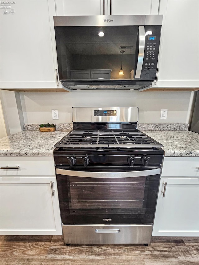 217 Ott St, Clyde, OH 43410 - kitchen featuring appliances with stainless steel finishes, wood finished floors, white cabinetry, and light stone countertops