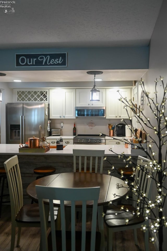 423 Leisure Dr, Huron, OH 44839 - kitchen with stainless steel appliances, white cabinets, dark wood finished floors, decorative light fixtures, and a textured ceiling