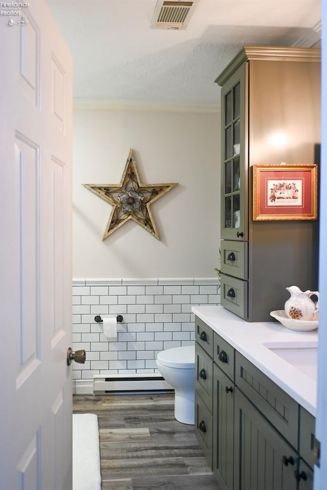 423 Leisure Dr, Huron, OH 44839 - bathroom with baseboard heating, wood finished floors, ornamental molding, vanity, and a wainscoted wall