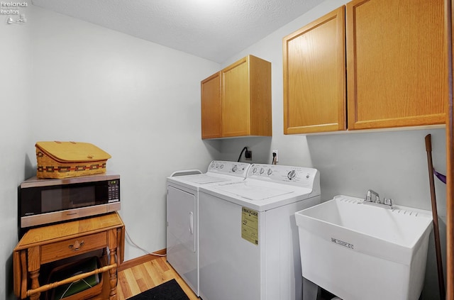 408 Forest St, Lagrange, OH 44050 - laundry area featuring separate washer and dryer, cabinet space, light wood-style flooring, and a textured ceiling