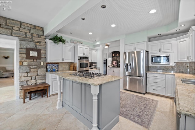 1115 Cedar Point Rd, Sandusky, OH 44870 - kitchen featuring appliances with stainless steel finishes, backsplash, a kitchen island, light stone countertops, and beamed ceiling