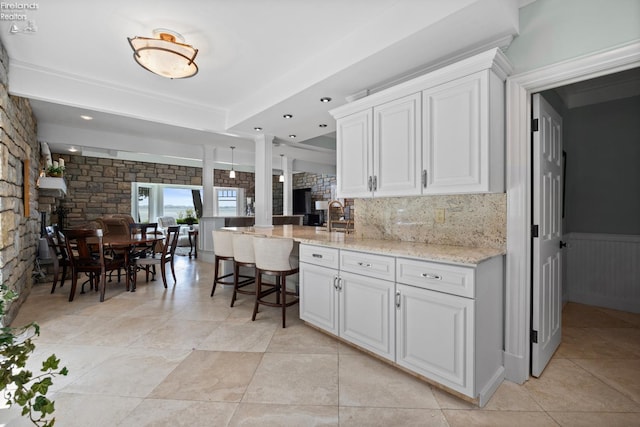 1115 Cedar Point Rd, Sandusky, OH 44870 - kitchen with light stone counters, white cabinets, backsplash, a peninsula, and light tile patterned floors