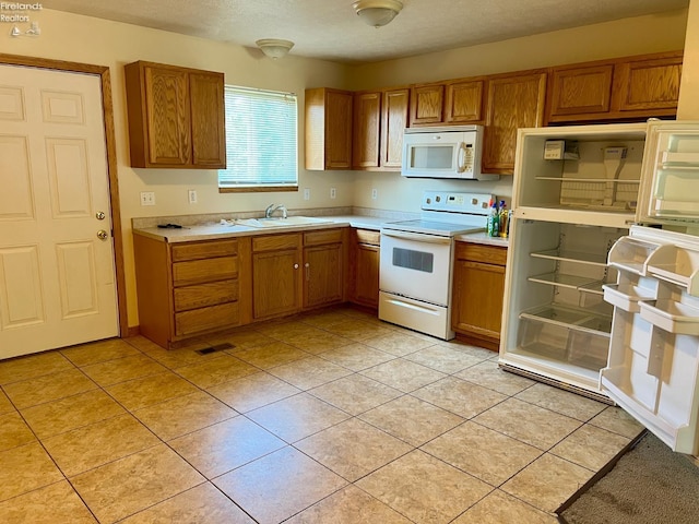 3106 E County Road 50, Tiffin, OH 44883 - kitchen with white appliances, brown cabinets, light countertops, light tile patterned floors, and a textured ceiling
