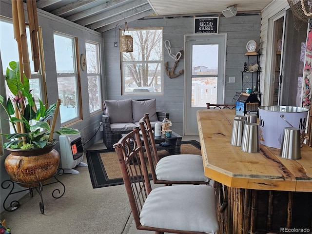 dining area featuring heating unit, wood walls, and vaulted ceiling