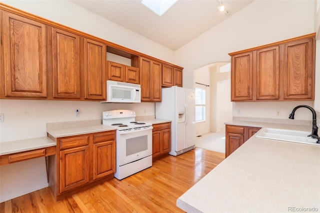 kitchen with white appliances, sink, lofted ceiling, and light hardwood / wood-style flooring