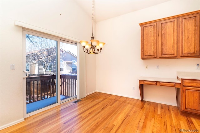 unfurnished dining area with a chandelier, built in desk, and light hardwood / wood-style flooring