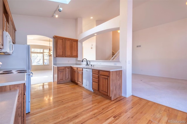 kitchen with stainless steel dishwasher, stove, sink, and light hardwood / wood-style flooring