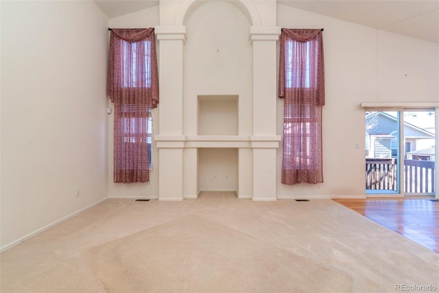 unfurnished living room featuring high vaulted ceiling and carpet