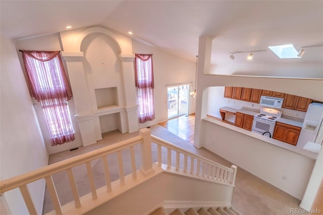 stairway featuring vaulted ceiling with skylight, rail lighting, and carpet flooring