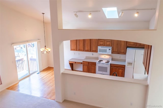 kitchen featuring light hardwood / wood-style floors, track lighting, white appliances, a notable chandelier, and pendant lighting