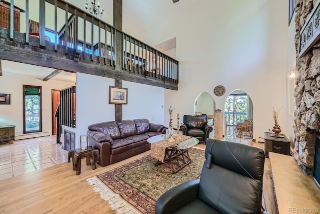 living room with a stone fireplace, hardwood / wood-style floors, a high ceiling, and a wealth of natural light