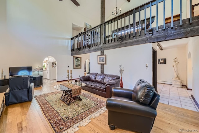 living room with a baseboard radiator, ceiling fan with notable chandelier, a high ceiling, and hardwood / wood-style flooring