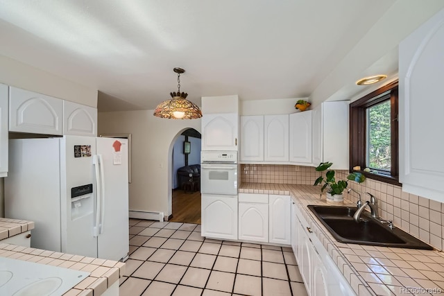 kitchen featuring a baseboard heating unit, white appliances, tile countertops, and white cabinets