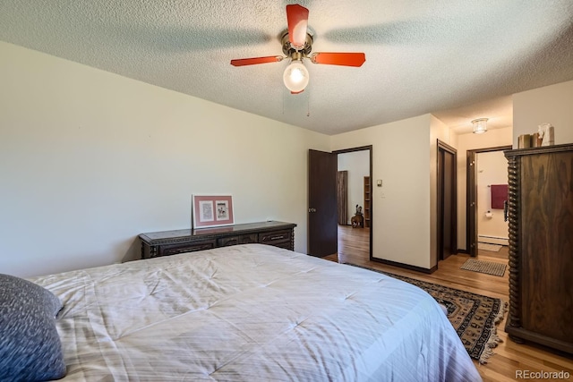 bedroom with ceiling fan, a textured ceiling, light hardwood / wood-style flooring, and a baseboard radiator