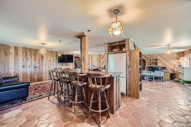 interior space featuring wooden walls, hanging light fixtures, and white fridge