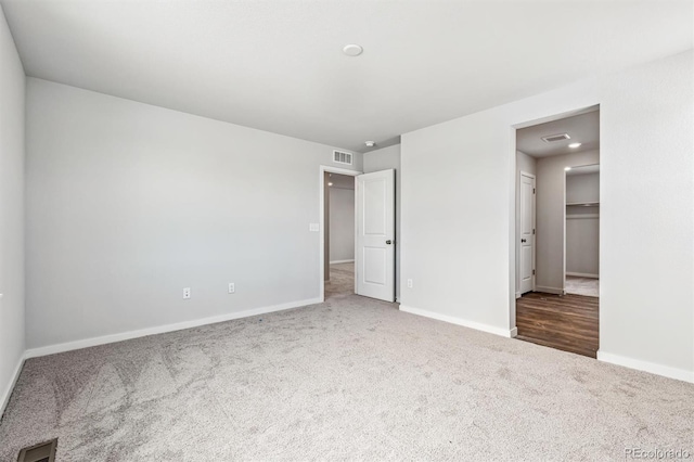 unfurnished bedroom featuring a walk in closet and carpet