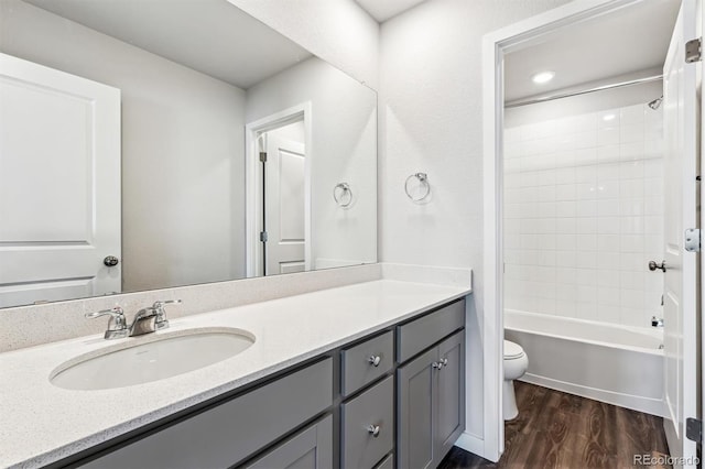 full bathroom featuring vanity, hardwood / wood-style floors, tiled shower / bath, and toilet