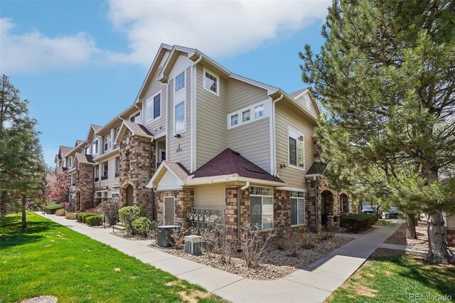 12711 Colorado Blvd Unit 1009, Thornton, CO 80241 - view of side of property featuring stone siding, a yard, and central air condition unit