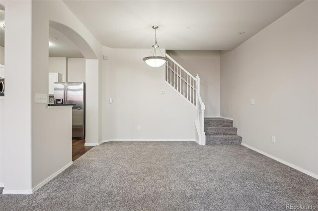 12711 Colorado Blvd Unit 1009, Thornton, CO 80241 - unfurnished living room featuring carpet floors, arched walkways, stairway, and baseboards