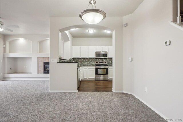 12711 Colorado Blvd Unit 1009, Thornton, CO 80241 - kitchen featuring stainless steel appliances, dark colored carpet, ceiling fan, a tile fireplace, and dark countertops