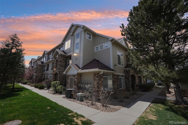 12711 Colorado Blvd Unit 1009, Thornton, CO 80241 - view of home's exterior featuring stone siding, a yard, and central air condition unit