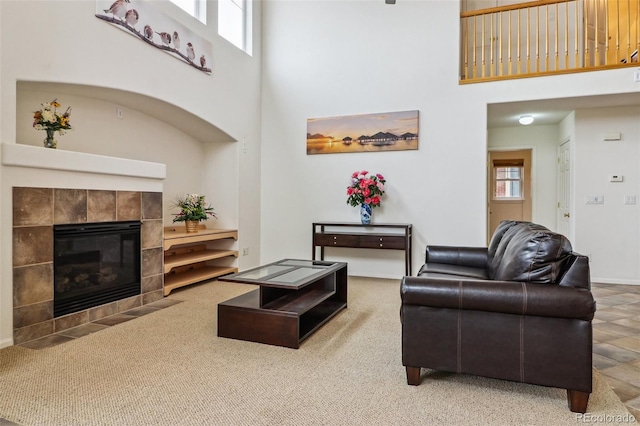 living area with a tile fireplace, a towering ceiling, and plenty of natural light