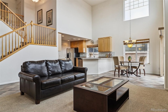 living area featuring an inviting chandelier, light colored carpet, stairway, light tile patterned flooring, and baseboards