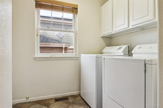clothes washing area featuring separate washer and dryer, baseboards, visible vents, and cabinet space