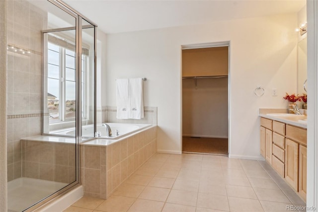 bathroom featuring vanity, a spacious closet, tile patterned flooring, a shower stall, and a garden tub