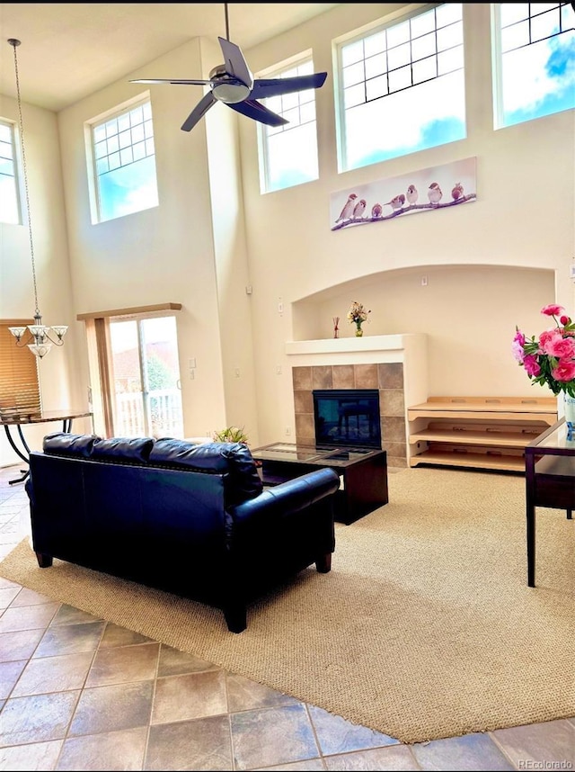 living room with a tiled fireplace, a ceiling fan, and plenty of natural light