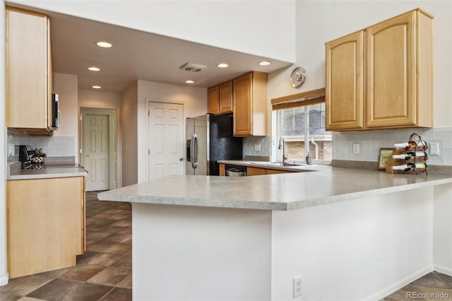 kitchen with light brown cabinets, a sink, light countertops, appliances with stainless steel finishes, and a peninsula