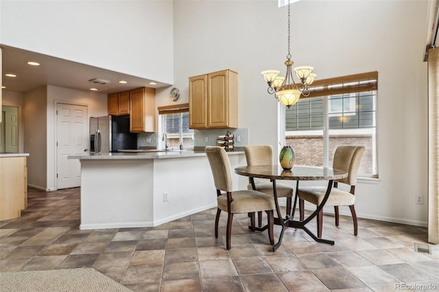 kitchen featuring tasteful backsplash, visible vents, stainless steel fridge, a notable chandelier, and a sink