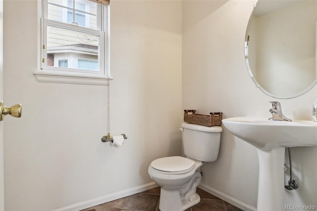 bathroom with toilet, baseboards, and tile patterned flooring