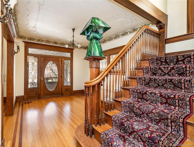 entryway with a chandelier, stairs, hardwood / wood-style flooring, and baseboards