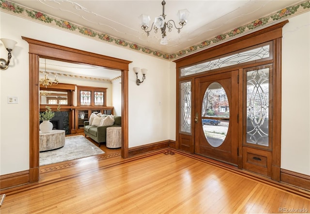 entryway featuring light wood finished floors, an inviting chandelier, baseboards, and plenty of natural light