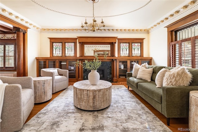 living area featuring a wealth of natural light, a fireplace, an inviting chandelier, and wood finished floors