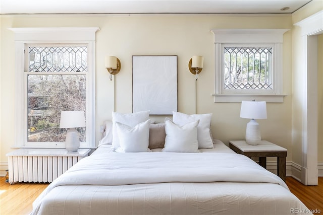 bedroom with radiator and wood finished floors