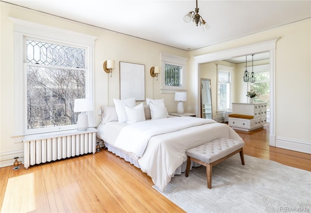 bedroom featuring radiator heating unit, an inviting chandelier, and wood finished floors